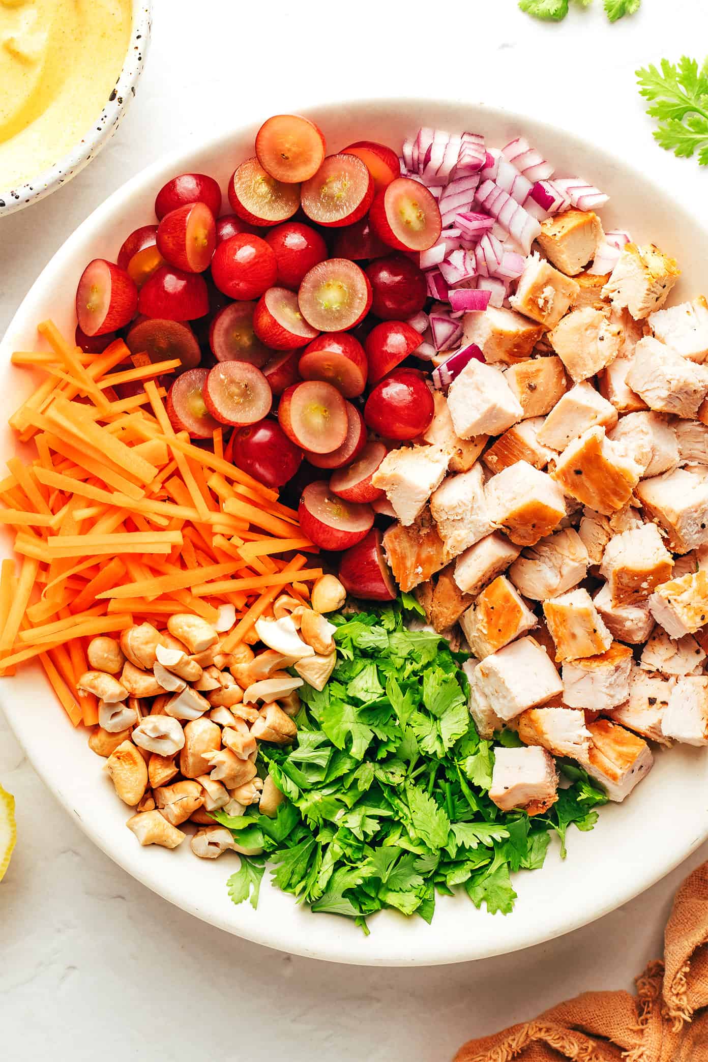 This copycat Trader Joe's curry chicken salad recipe is made with diced chicken, grapes, carrots, cashews, red onions, and a creamy Greek yogurt curry sauce. Serve in sandwiches, lettuce wraps, with crackers for dipping, or whatever sounds good! It's a high protein recipe that's perfect for meal prep and always hits the spot. | gimmesomeoven.com Curry chicken salad ingredients in bowl