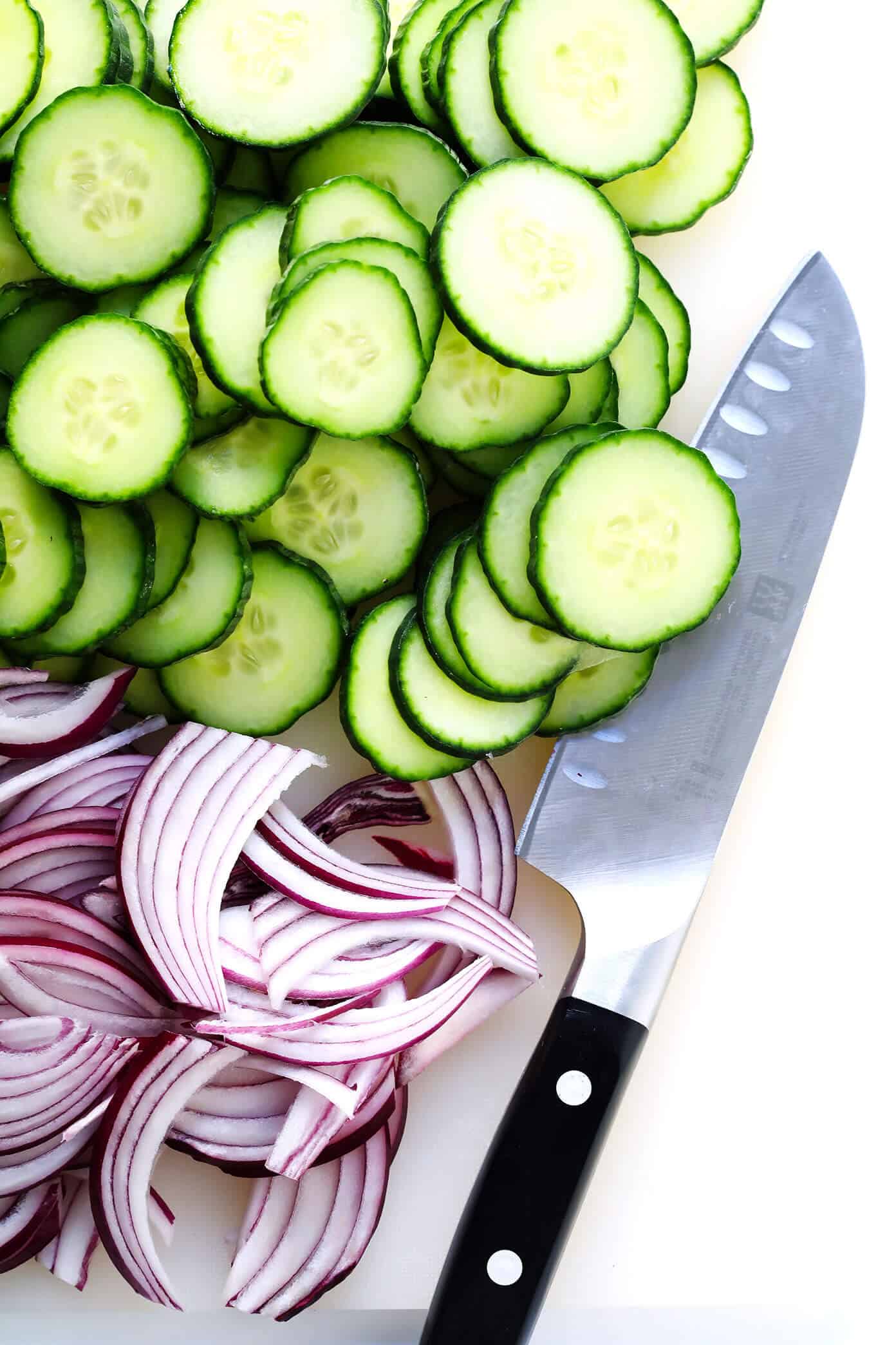 My favorite everyday salad recipe -- made with fresh greens, cucumber, red onion, pepitas (or your favorite nuts), and a simple lemon salad dressing. So easy, healthy and delicious! | gimmesomeoven.com #healthy #salad #recipe #dinner #vegetarian #vegan #glutenfree #easy #dressing #vinagirette Slicing English cucumber and red onion to make a side salad