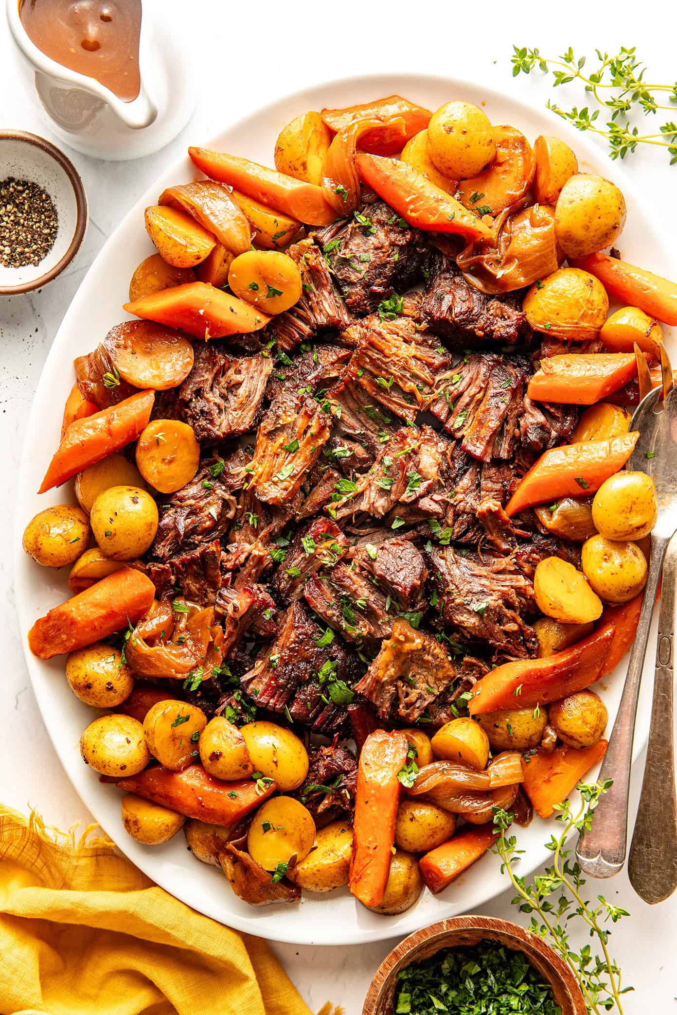 pot roast on a platter with carrots, onions, potatoes and gravy