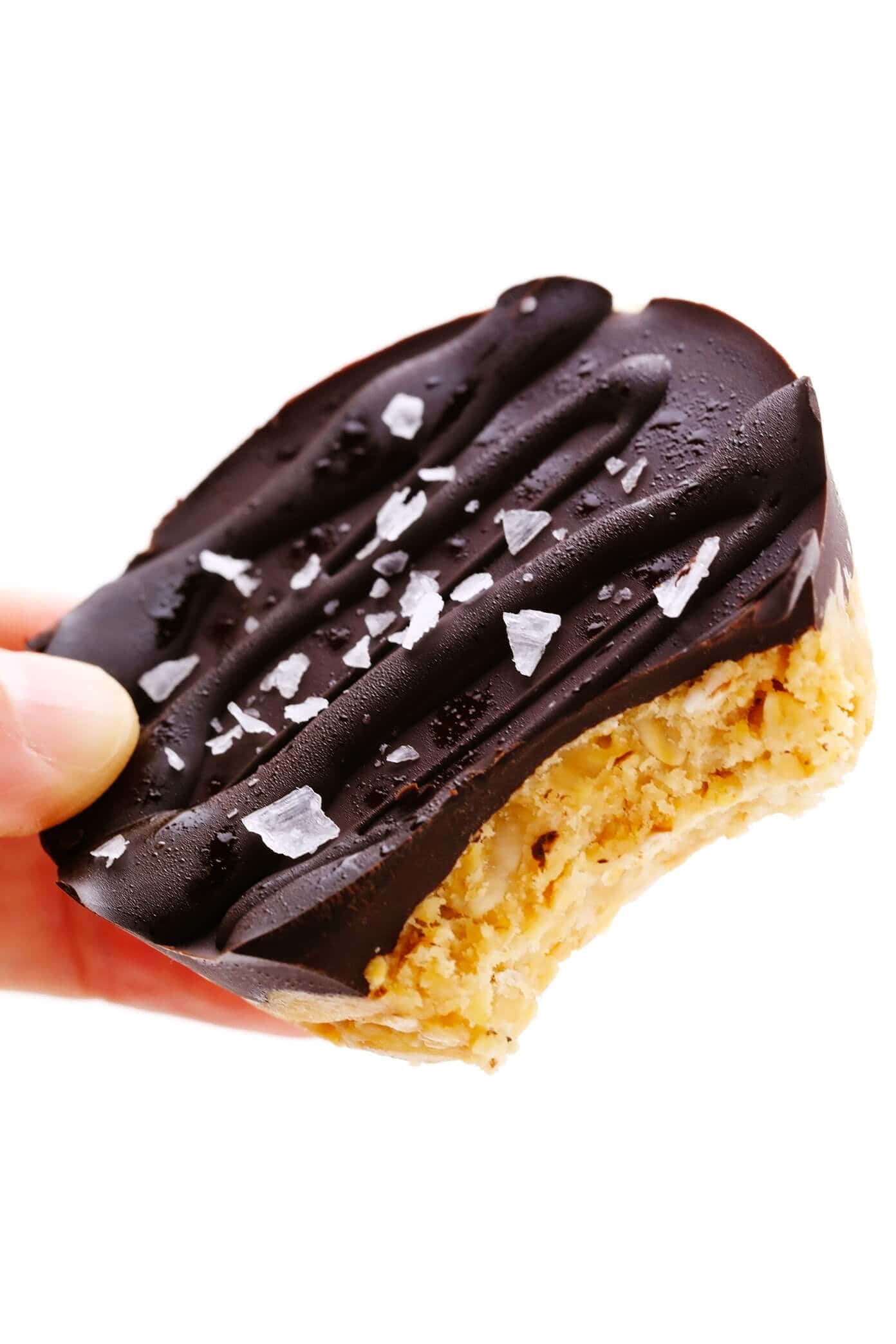 These salted chocolate peanut butter oat cups are quick and easy to make, naturally sweetened with honey, and always SO tasty! They are the perfect treat for breakfast, dessert, or a healthy snack. And they are gluten-free and vegan too! | gimmesomeoven.com Holding a Salted Chocolate Peanut Butter Oat Cup